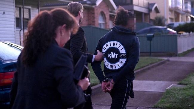 Wearing a KVT jacket, the man is led away by NSW Police officers. Picture: Jeremy Piper