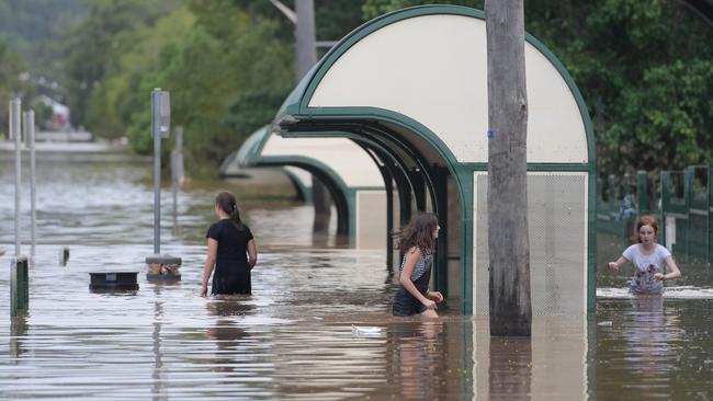 Girls walk through floodwaters as they recede in Lismore. Picture: AAP