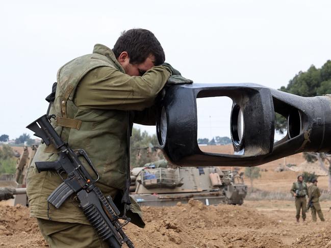 TOPSHOT - An Israeli soldier rests his head on an artillery gun barrel of an armoured vehicle as Israeli soldiers take positions near the border with Gaza in southern Israel on October 9, 2023. Stunned by the unprecedented assault on its territory, a grieving Israel has counted over 700 dead and launched a withering barrage of strikes on Gaza that have raised the death toll there to 493 according to Palestinian officials. (Photo by JACK GUEZ / AFP)