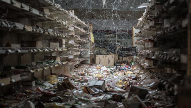 An aisle of a supermarket with products left on the floor. Since the disaster nature has been at work and cobwebs now hang between the shelves. Picture: Arkadiusz Podniesinski/REX Shutterstock