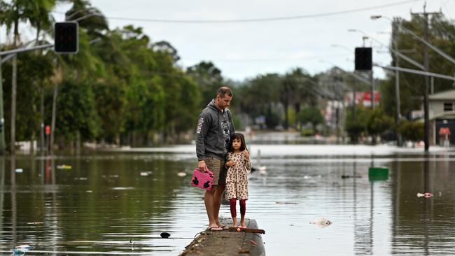 A father and his young daughter inspect a flooded street in Lismore on March 31, 2022. Picture: Dan Peled/Getty Images