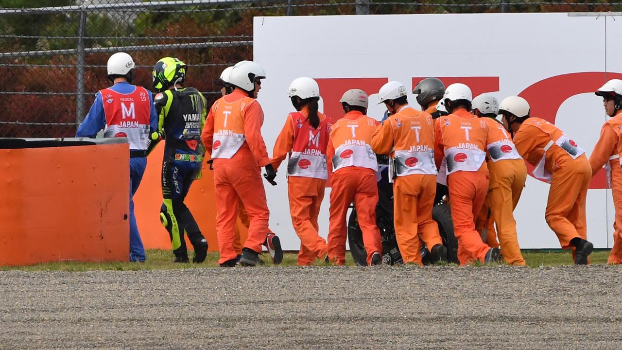 Valentino Rossi is flanked by marshals after crashing in Japan.