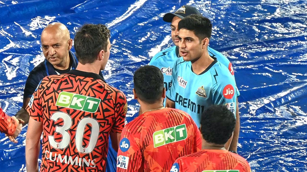 Gujarat Titans' captain Shubman Gill (R) and his Sunrisers Hyderabad's counterpart Pat Cummins (2L) greet each other after the IPL match was abandoned due to rain. (Photo by NOAH SEELAM / AFP)