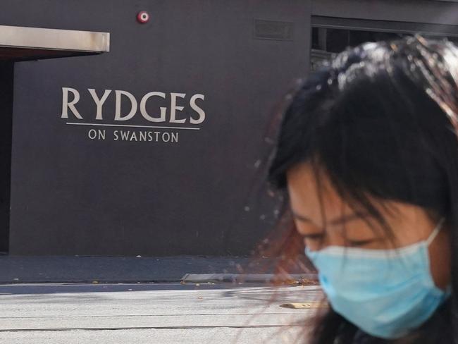 A person wearing a face mask walks past the Rydges on Swanston hotel in Melbourne, Sunday, May 31, 2020. A coronavirus cluster in Melbourne's northwest has infected 13 people across two homes, closed two schools and forced more than 100 students to self-isolate. (AAP Image/Scott Barbour) NO ARCHIVING