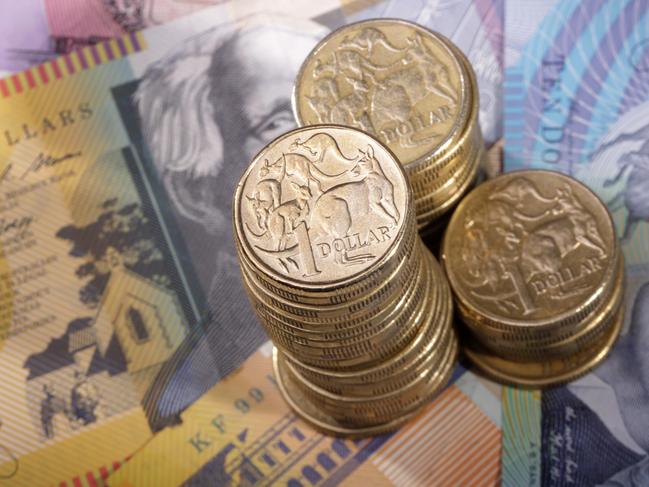 Three stacks of Australian one dollar coins on a background of bank notes. Shallow depth of field focus on tallest stack., cash money generic