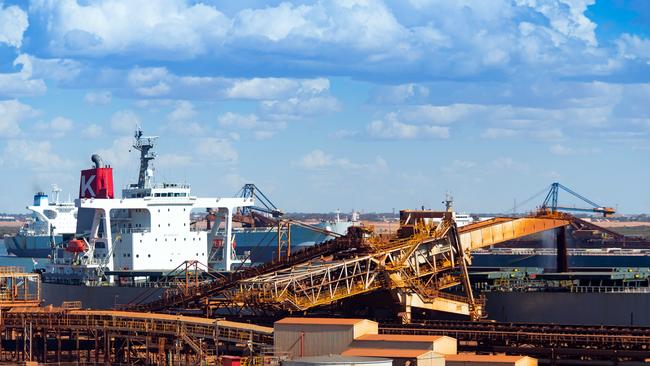 Iron ore falls from a conveyor into a bulk carrier at the port in Port Hedland, Australia. Photographer: Picture: Getty Images