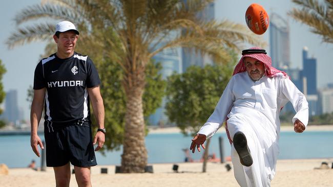 Carlton coach Brett Ratten teaches local Wageh Khlelle how to kick the footy.