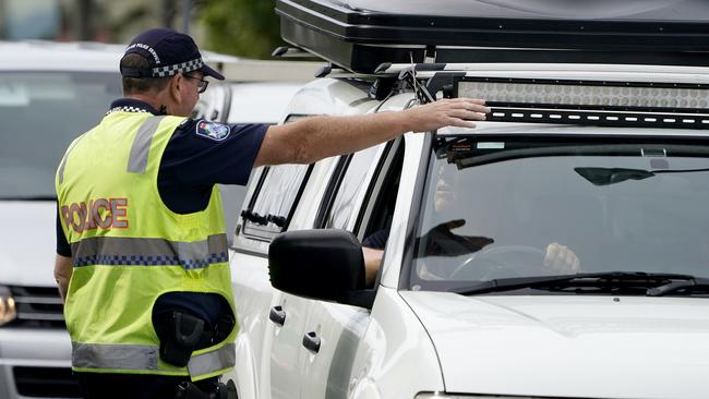 A Queensland police officer gestures for a motorist to pull over at a checkpoint at Coolangatta on the Queensland-New South Wales border last Friday. Picture: AAP Image/Dave Hunt