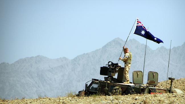 An Australian soldier erects an Australian flag on his Bushmaster infantry mobility vehicle in the Tarin Kowt region. Picture: Defence