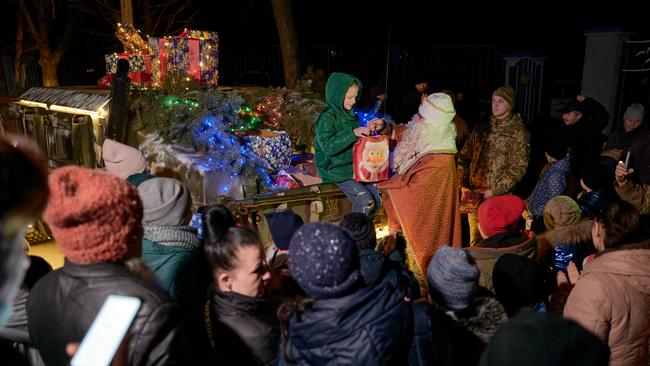 Children receive presents from an Ukrainian soldier disguised as Saint Nicholas near a military vehicle decorated with Christmas lights on December 24 in Sloviansk.