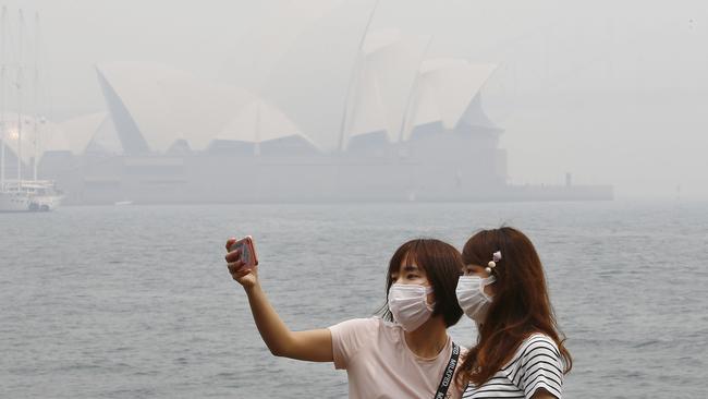 Masked Tourists pose for an Opera House view selfie at Mrs Macquarie's Chair … but there's not much to see. Picture: John Appleyard