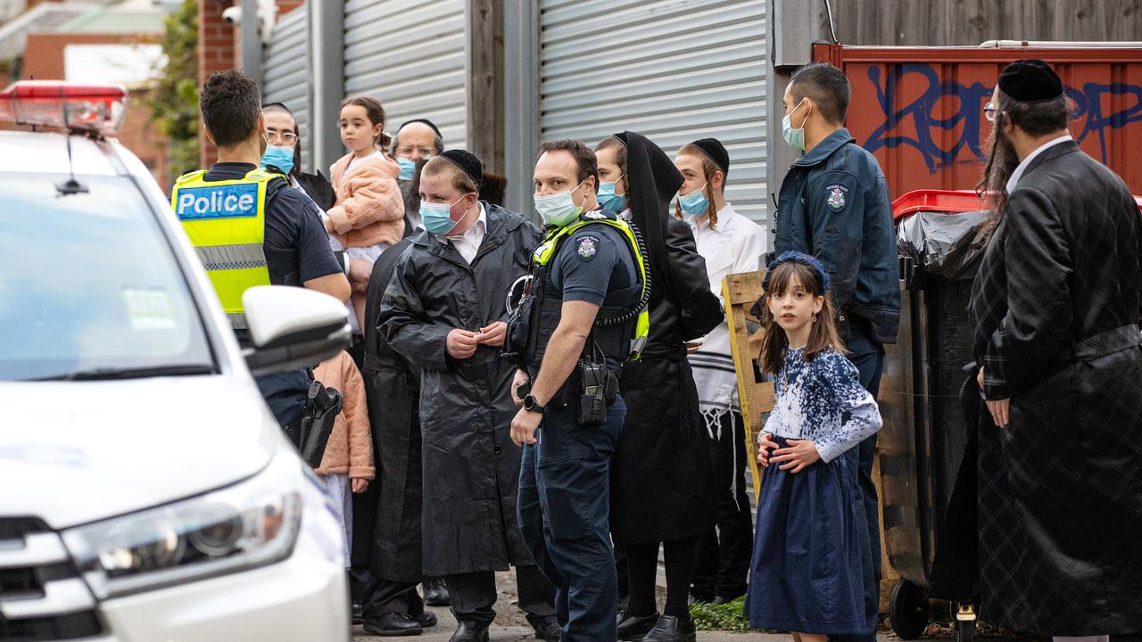 Members of the Caulfield Jewish community speak with police as fellow community members wait to leave an illegal gathering. News Corp is not suggesting these people are connected to the video footage in this story. Picture: Mark Stewart