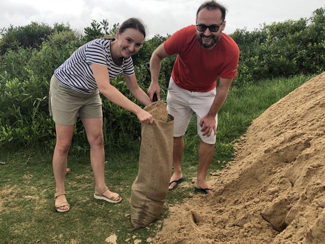 Mona Vale couple Magda and Pawel were filling bags at the car park near the North Narrabeen Surf Life Saving Club on Wednesday morning. Picture: Jim O'Rourke