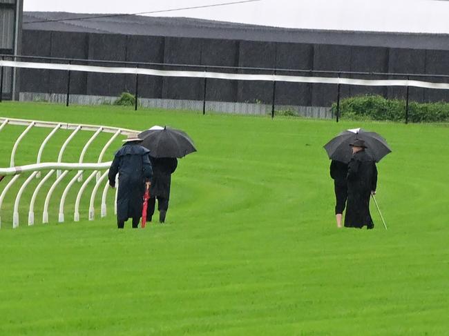 Racing officials inspect the Doomben track after heavy rain battered Brisbane ahead of the Doomben Cup. Picture: Grant Peters - Trackside Photography.