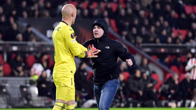 A pitch invader (R) attempts an assault on Sevilla FC goalkeeper Marko Dmitrovic (L) during the UEFA Europa league play-off match between PSV Eindhoven and Sevilla FC at the Phillips stadium in Eindhoven.