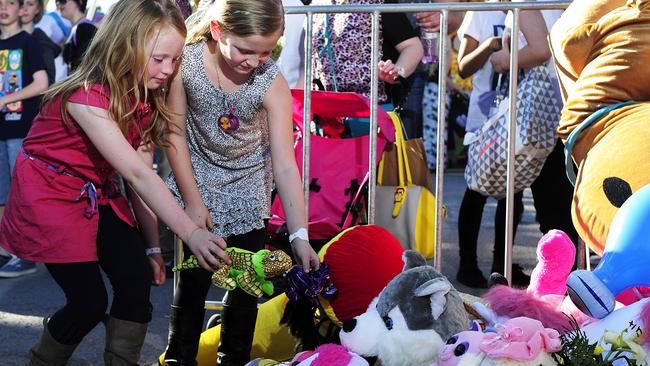 Two girls place a toy at a memorial that show patrons created after Adelene Leong died. Picture: Mark Brake