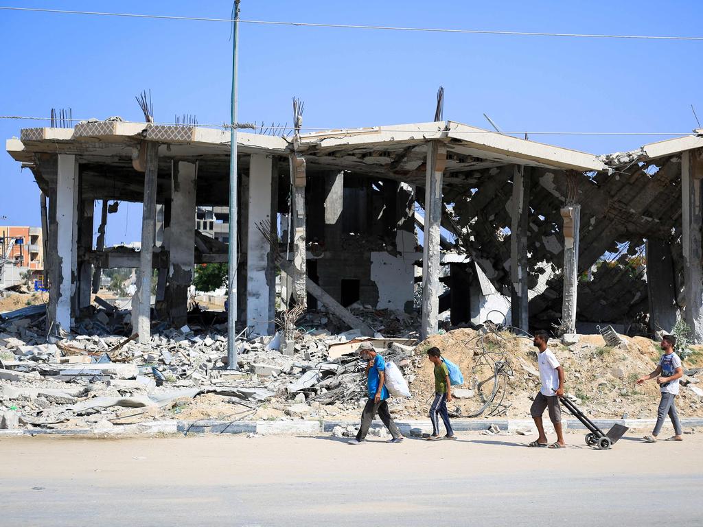 Displaced Palestinians carry belongings as they walk in front of a destroyed building in Deir el-Balah in the central Gaza Strip. Picture: AFP
