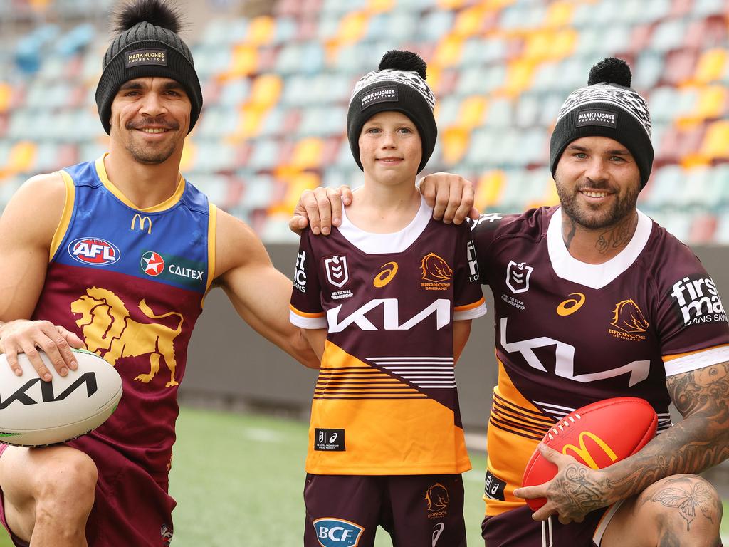 Lions player Charlie Cameron, Harry Wiseman, 7, and Broncos player Adam Reynolds, with their Mark Hughes Foundation beanies at the Gabba. Picture: Liam Kidston