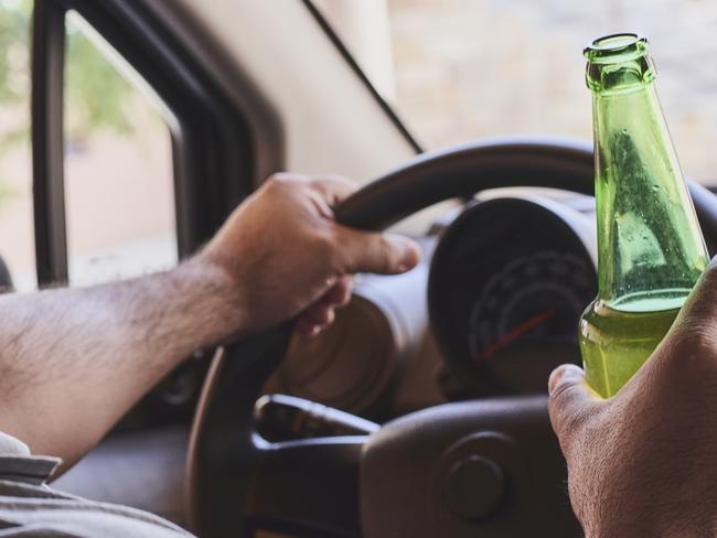 An unrecognizable man drinking beer while driving car. Concepts of driving under the influence, drunk driving or impaired driving. Drink driving generic. Picture: iSTOCK