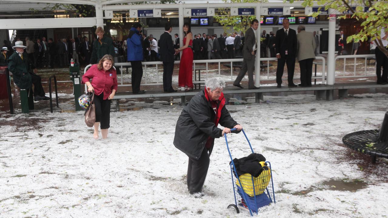 Racegoers negotiate flood water and hail in the betting ring. Picture: AAP