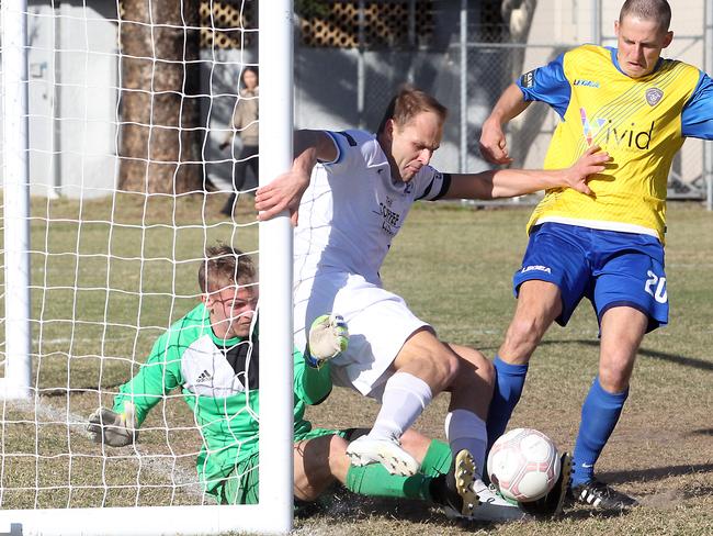 Surfers Paradise’s Teddy Watson (centre) fights to scramble the ball home against Broadbeach United yesterday. Picture: Richard Gosling