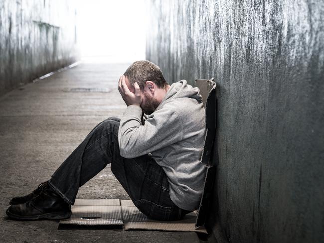 Young homeless male of caucasian ethnicity sitting on the floor of a dark subway tunnel with his hands on his head. Desaturated horizontal colour image with lots of room for copy space. LEV pg 8-9homeless man tunnel 2 iSTOCK