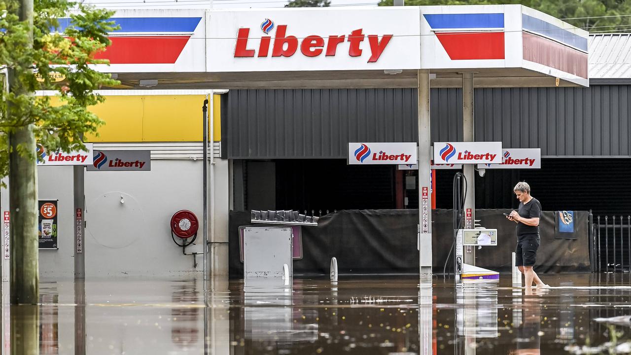 A man walks through flood waters a petrol station in Lismore. Picture: Darren Leigh Roberts