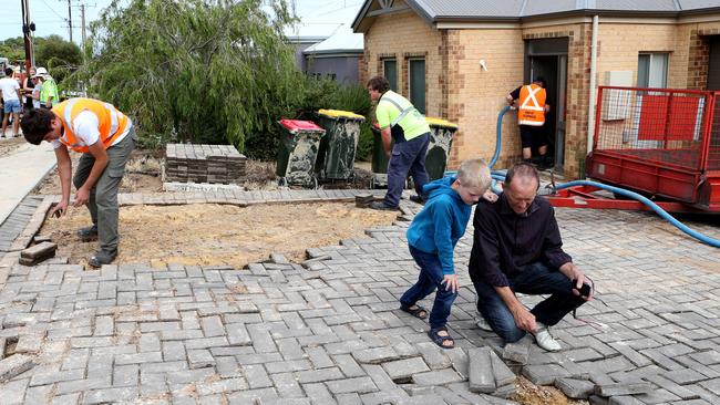 Landlord John Eckermann with his grandson Jasper, 7, looks at the damage to a driveway after the water main burst.