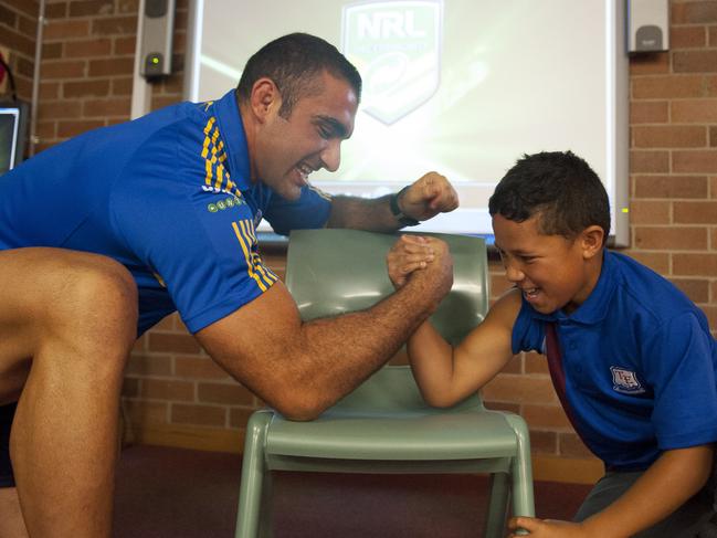 NRL player Tim Mannah arm wrestles with a student during a Parramatta Eels visit to Toongabbie East Public School as part of wellbeing initiative.