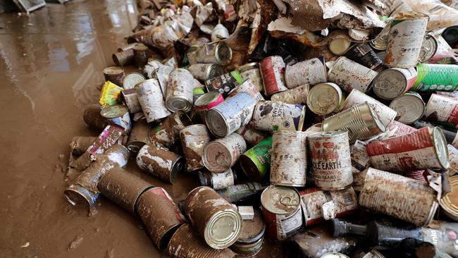 Cans of food are piled up on the footpath outside a shop on Keen St, Lismore after being damaged in the flood waters. Picture: Toby Zerna