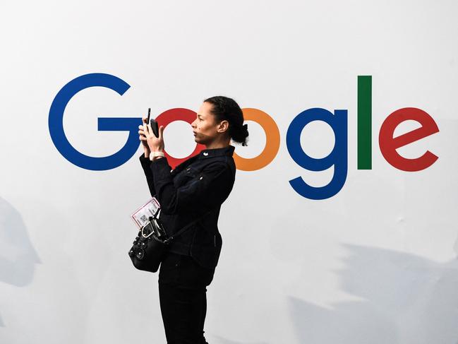 (FILES) In this file photo taken on May 16, 2019, a woman takes a picture with two smartphones in front of the logo of the US multinational technology and Internet-related services company Google as she visits the Vivatech startups and innovation fair, in Paris. - Google said on February 22, 2020 it would lift its ban on political ads on its platform imposed last month following the turmoil surrounding the violent uprising at the US Capitol. (Photo by ALAIN JOCARD / AFP)