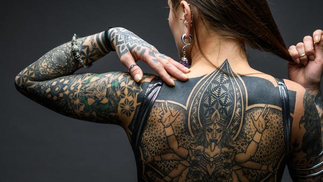 Tattooed girl studio portrait on gray background; tattoo generic