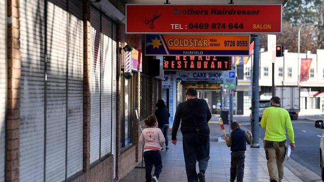 A family walk in front of shuttered shops during lockdown in the Fairfield in Sydney‘s southwest. Picture: AFP