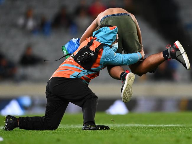 AUCKLAND, NEW ZEALAND - MAY 06: A pitch invader is tackled during the round 12 Super Rugby Pacific match between the Blues and the Melbourne Rebels at Eden Park on May 06, 2022 in Auckland, New Zealand. (Photo by Hannah Peters/Getty Images)