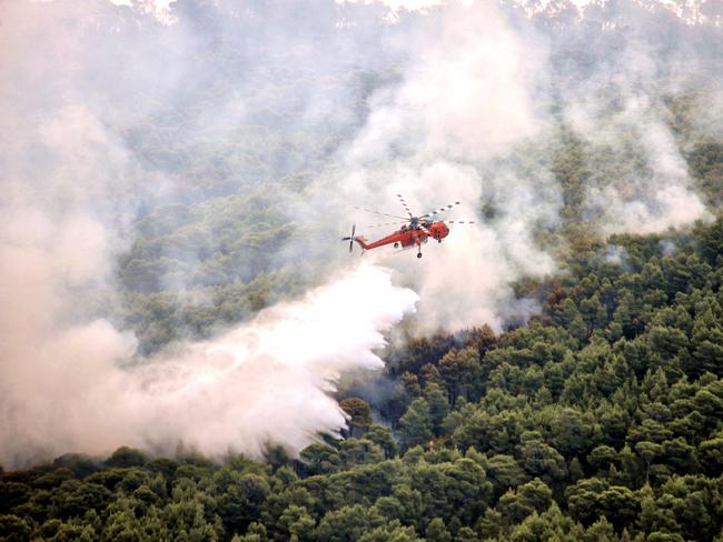 A firefighting helicopter drops water to extinguish flames during a wildfire at the village of Kineta, near Athens. Picture: AFP