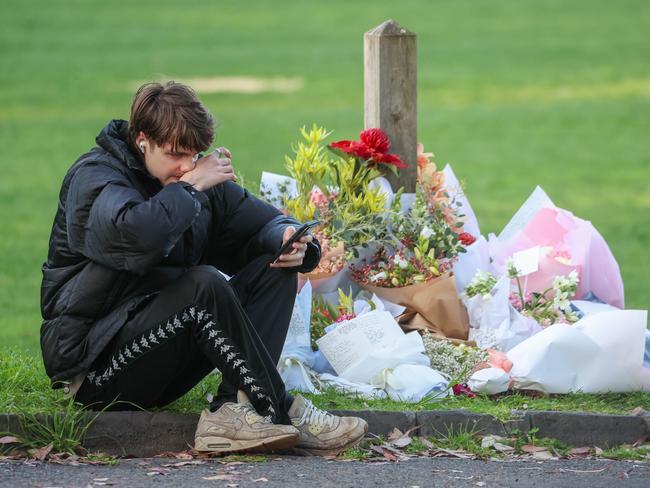 A man sits at a flower tribute for Elise Hodder who died in Kooyong. Picture: Brendan Beckett