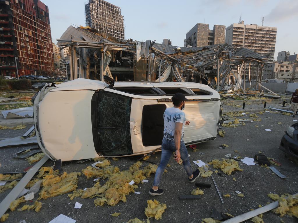 A man walks by an overturned car and destroyed buildings. Picture: Marwan Tahtah/Getty Images