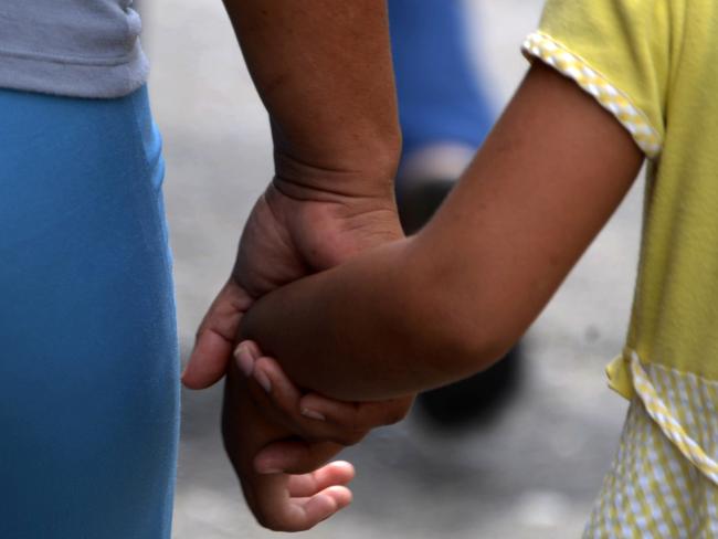 Fifty-two-year-old Geraldina, who had three sons killed by gang members, takes her daughter by the hand as they walk through a street in Honduras. Picture: Orlando Sierra/AFP