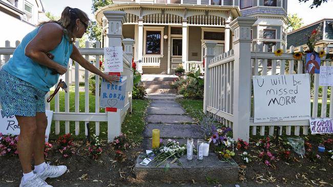 Boulder resident Wendy Darling tapes up a sign that reads "Fly Be Free Robin," as she pays tribute to Robin Williams at a makeshift memorial outside the home where the 80s TV series "Mork &amp; Mindy," was filmed. Picture: Brennan Linsley