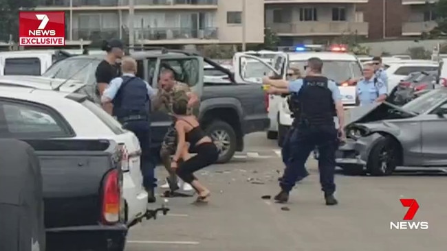 Police confront five people in the carpark behind Dee Why surf club on Monday. Picture 7News