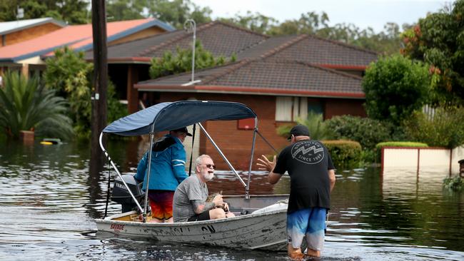 Jack Jennings with his cat Buffy being rescued in floodwaters in North Haven, near Port Macquarie. Picture: Nathan Edwards