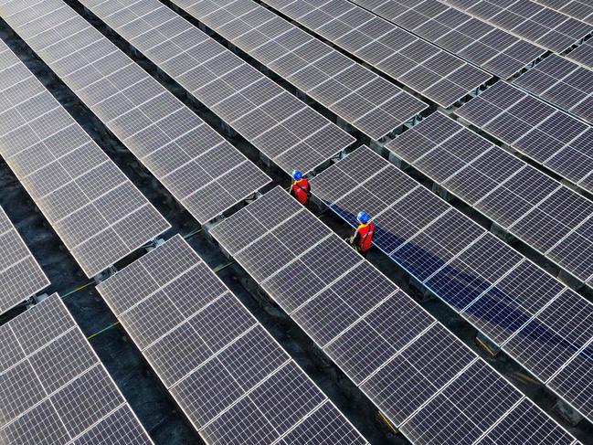 TOPSHOT - This photo taken on February 21, 2024 shows workers inspecting solar panels at a rooftop of a power plant in Fuzhou, in southern China's Fujian province. (Photo by AFP) / China OUT