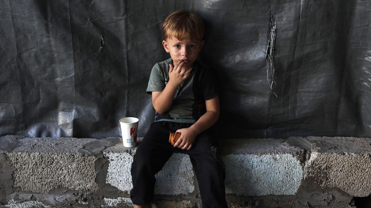 A child sits holding his biscuits at the Jabalia camp for displaced Palestinians in northern Gaza on August 29, 2024, amid the ongoing conflict between Israel and the militant Hamas group. (Photo by Omar AL-QATTAA / AFP)