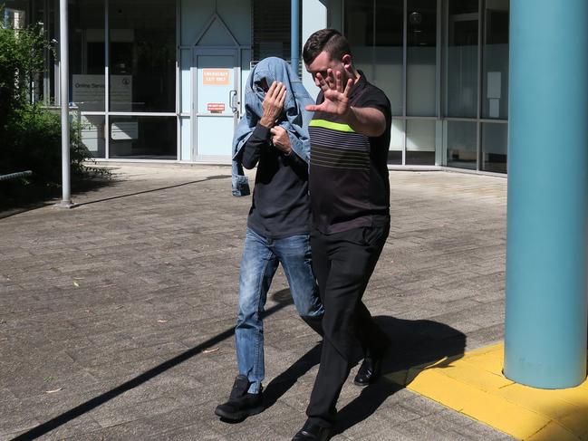 Sirens Nightclub owner Ross Glynatsis (covered) leaving court with a supporter after he was charged with drug and firearm offences. Picture: Richard Noone