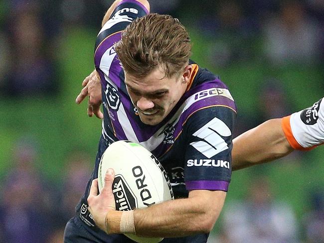 Ryan Papenhuyzen of the Storm (left) runs the ball forward under pressure from Luke Brooks of the Tigers during the Round 10 NRL match between the Melbourne Storm and the Wests Tigers at AAMI Park in Melbourne, Thursday, May 16, 2019.  (AAP Image/Hamish Blair) NO ARCHIVING, EDITORIAL USE ONLY