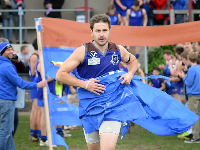 Old Peninsula one-club champion Shaun Payze runs through a banner for his 300th game.