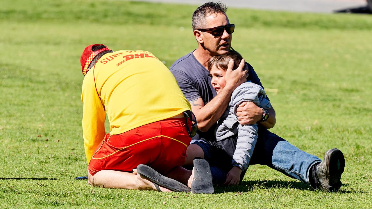 A surf lifesaver helping Isaiah, 11, who was stung by a bee as father Nicholas Collison comforts the boy. Picture: Matt Loxton