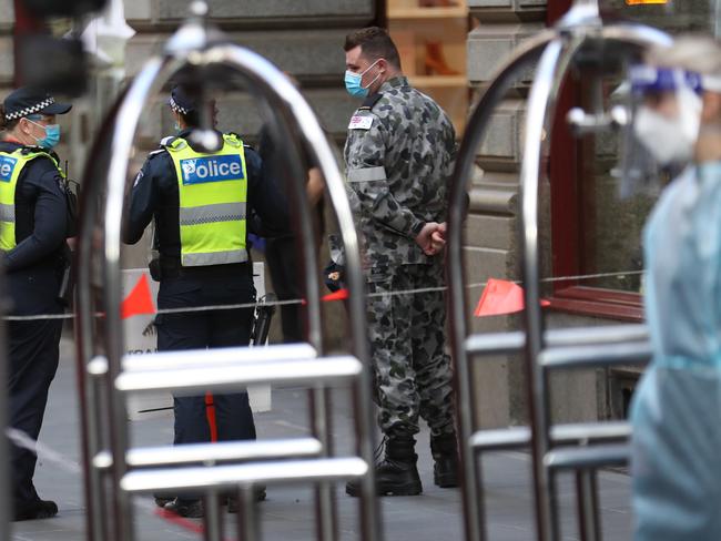 Passengers are taken from an airport bus into the Novotel Hotel on Collins St to complete hotel quarantine. Picture: David Crosling