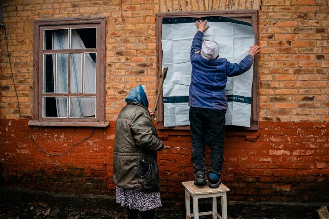 Elderly women place a plastic sheet over a broken window after shelling in Chasiv Yar, eastern Ukraine