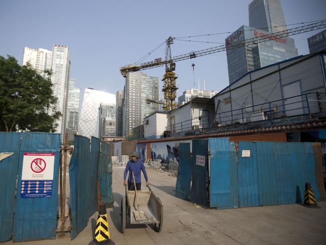 Growing ... a worker pushes a cart as he walks out from a construction site at the Central Business District in Beijing. AP Photo/Andy Wong